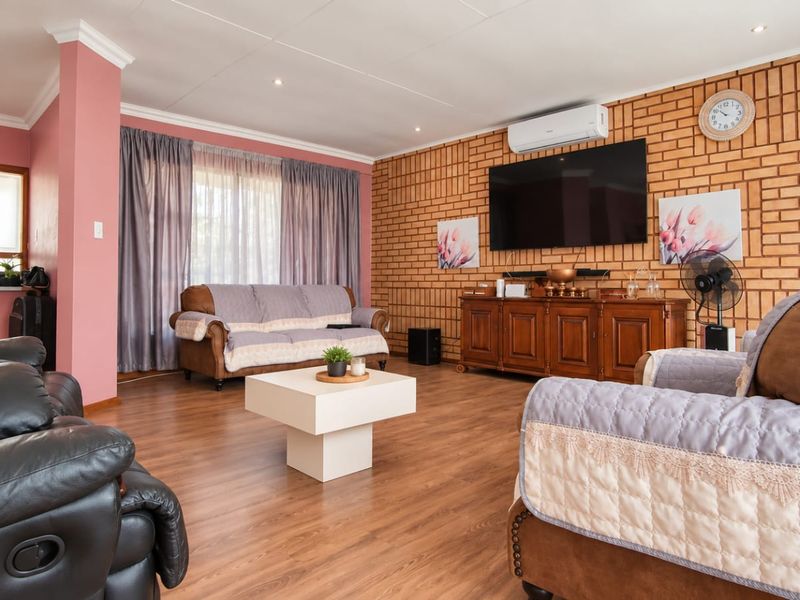 Spacious living room featuring an exposed brick feature wall, laminate flooring, and a split-system air conditioner, providing a comfortable and inviting atmosphere.