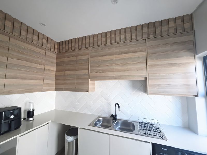 Modern kitchen featuring light wood-grain cabinetry, a white herringbone tile backsplash, and a double bowl stainless steel sink with a contemporary black faucet.