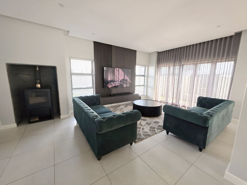 Modern living room featuring a built-in fireplace, slatted feature wall, large sliding doors with sheer curtains, and neutral tiled flooring.
