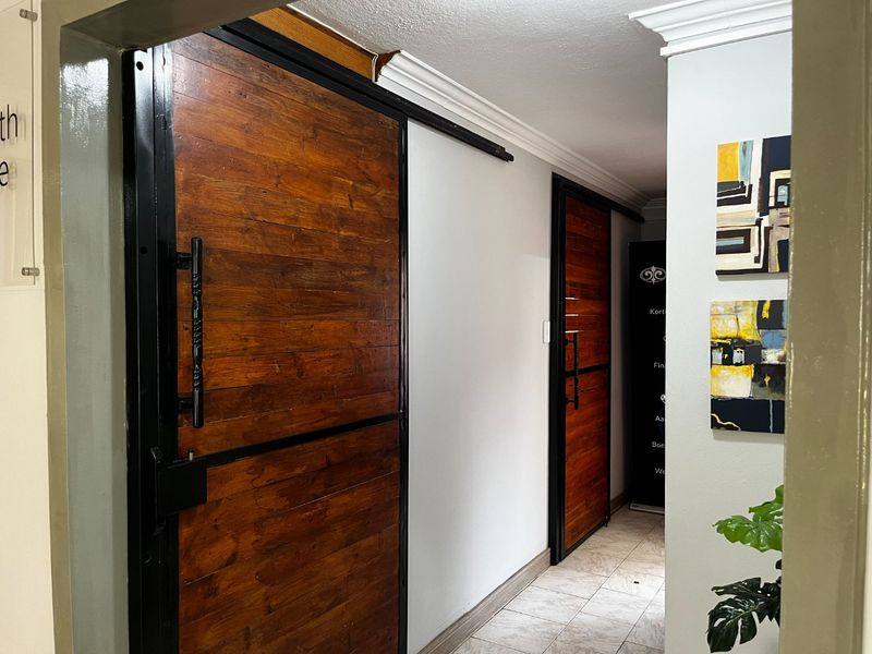 A well-maintained commercial hallway featuring modern sliding wooden barn doors, crown molding, and clean tiled flooring.