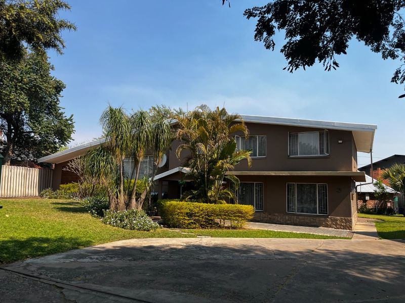 Front view of a two-story commercial property featuring a paved driveway, landscaped garden, and stone cladding accents on the building facade.