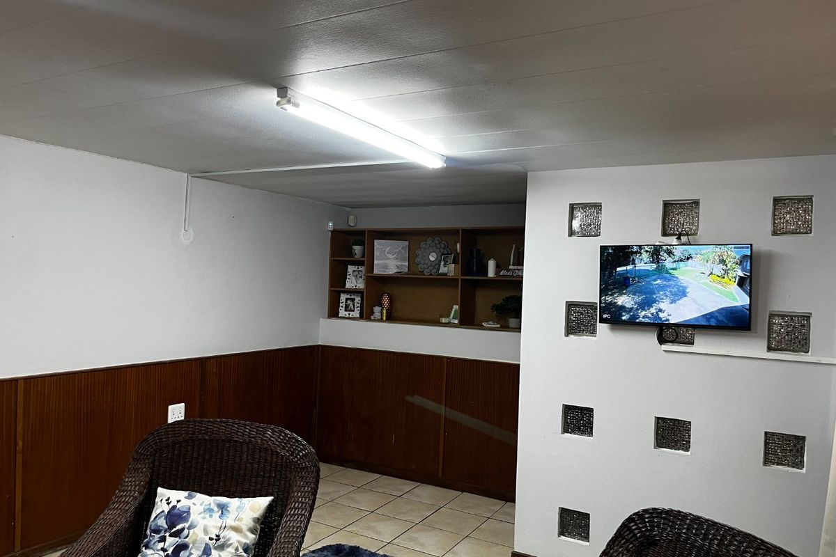 A living area featuring built-in shelving, decorative glass block wall inserts, and wood paneling, providing a functional space with potential for modernization.
