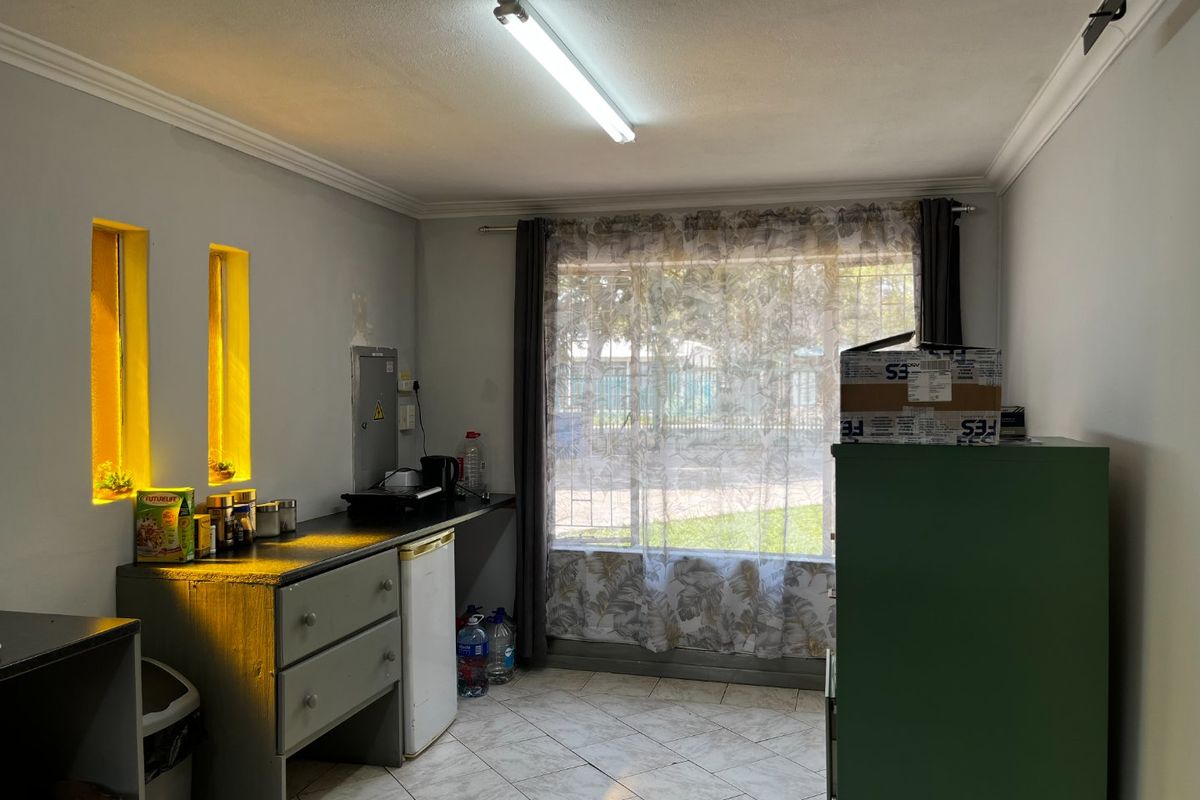 A functional kitchen area featuring tiled flooring, built-in cabinetry, and natural light through a large window, suitable for modernization and cosmetic updates.