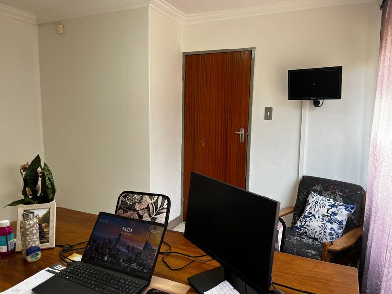 A functional office space featuring a timber door, coving, and a wall-mounted television bracket, providing a practical layout for a professional work environment.