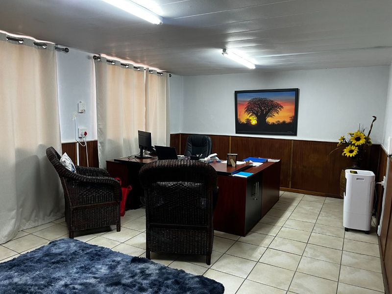 A functional commercial office space featuring tiled flooring, wood wall paneling, and overhead fluorescent lighting.