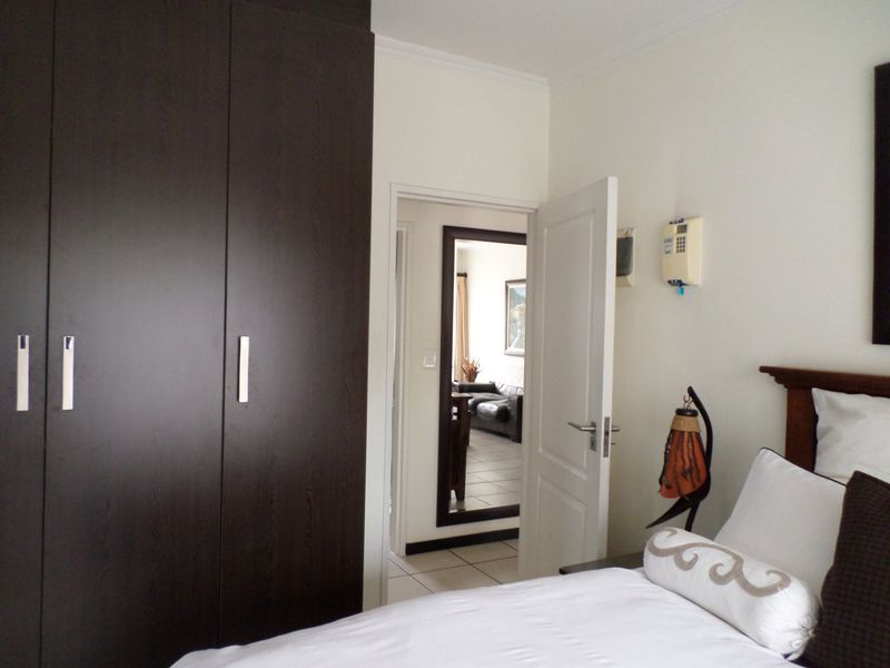 A bedroom featuring dark wood built-in cupboards and an intercom system, with a doorway leading to an adjacent living area.