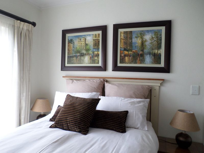 A well-maintained bedroom featuring neutral walls, a curtain rod, and a light switch, providing a comfortable and functional living space.