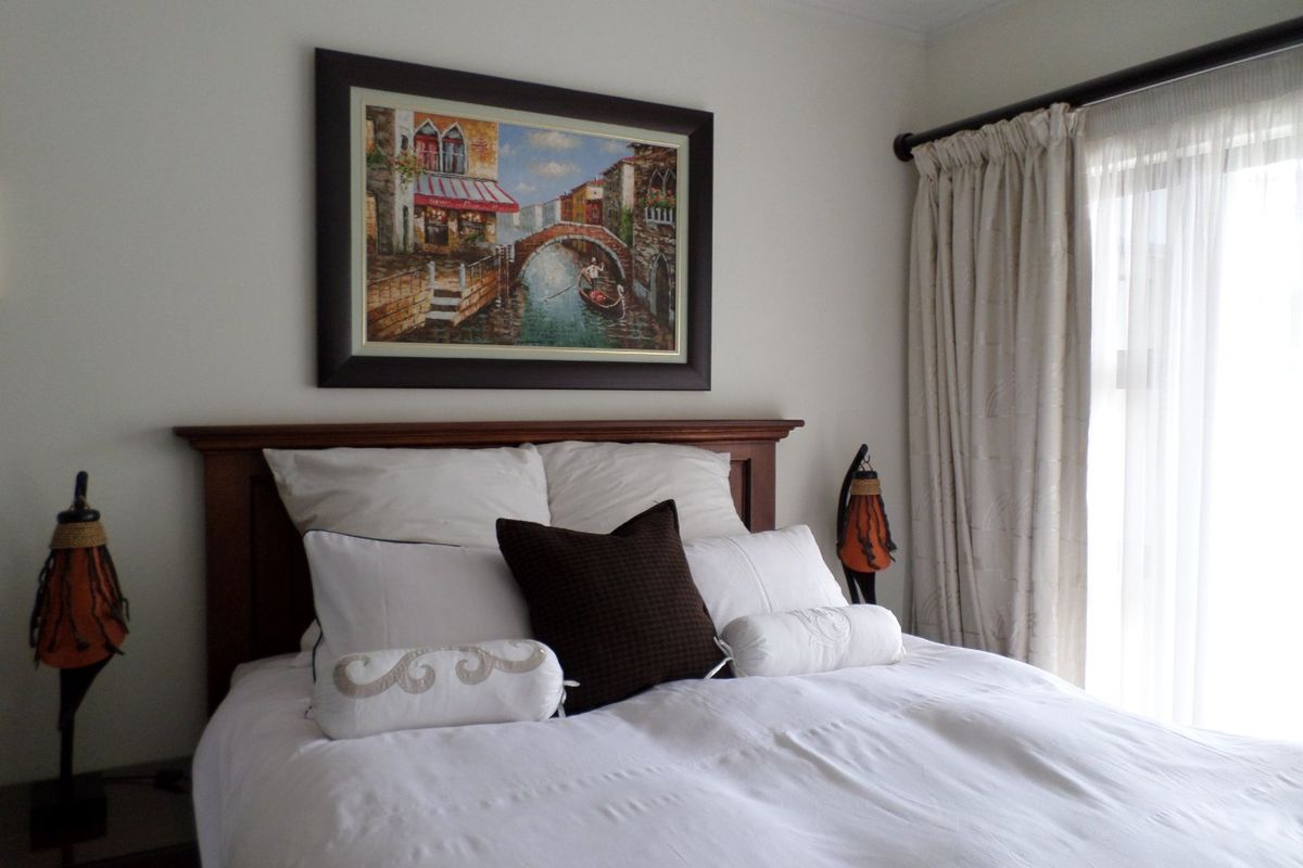 A well-maintained bedroom featuring neutral wall finishes, a curtain rod with drapes, and natural light from the adjacent window.