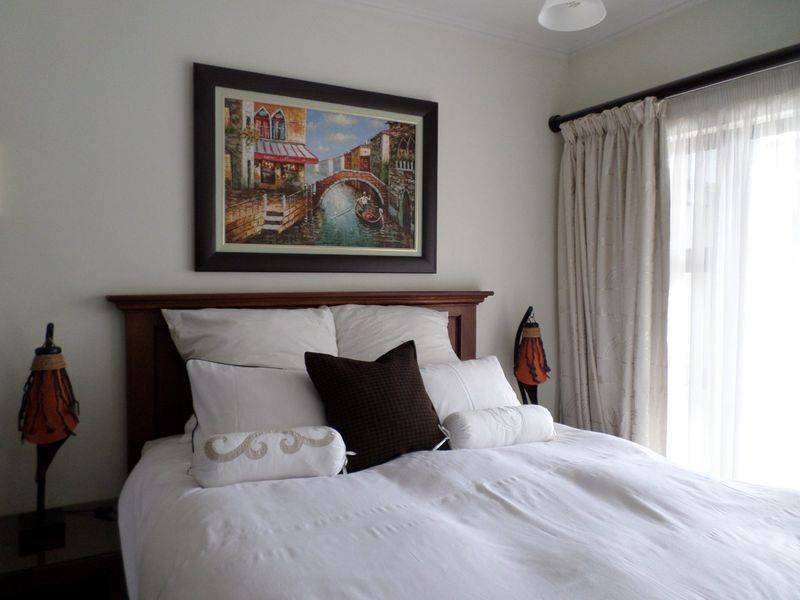 A well-maintained bedroom featuring neutral wall finishes, a curtain rod with drapes, and natural light from the adjacent window.