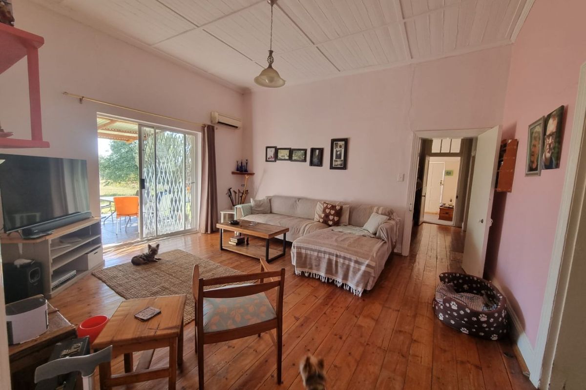 Spacious living room featuring original timber flooring, a timber ceiling, and a sliding glass door providing direct access to the outdoor patio area.
