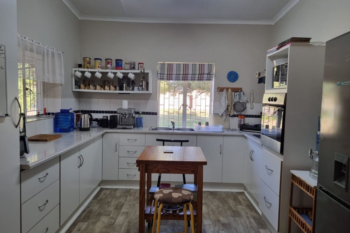 A functional kitchen featuring white cabinetry, laminate countertops, a built-in oven, and a tiled backsplash with natural light from two windows.
