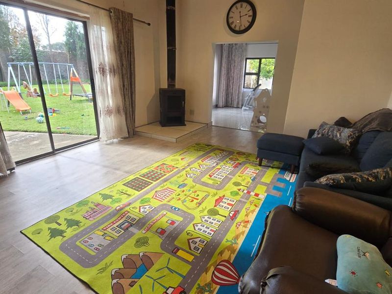 Spacious living room featuring a wood-burning stove, timber-clad ceiling, and large sliding glass doors providing direct access to the rear garden.