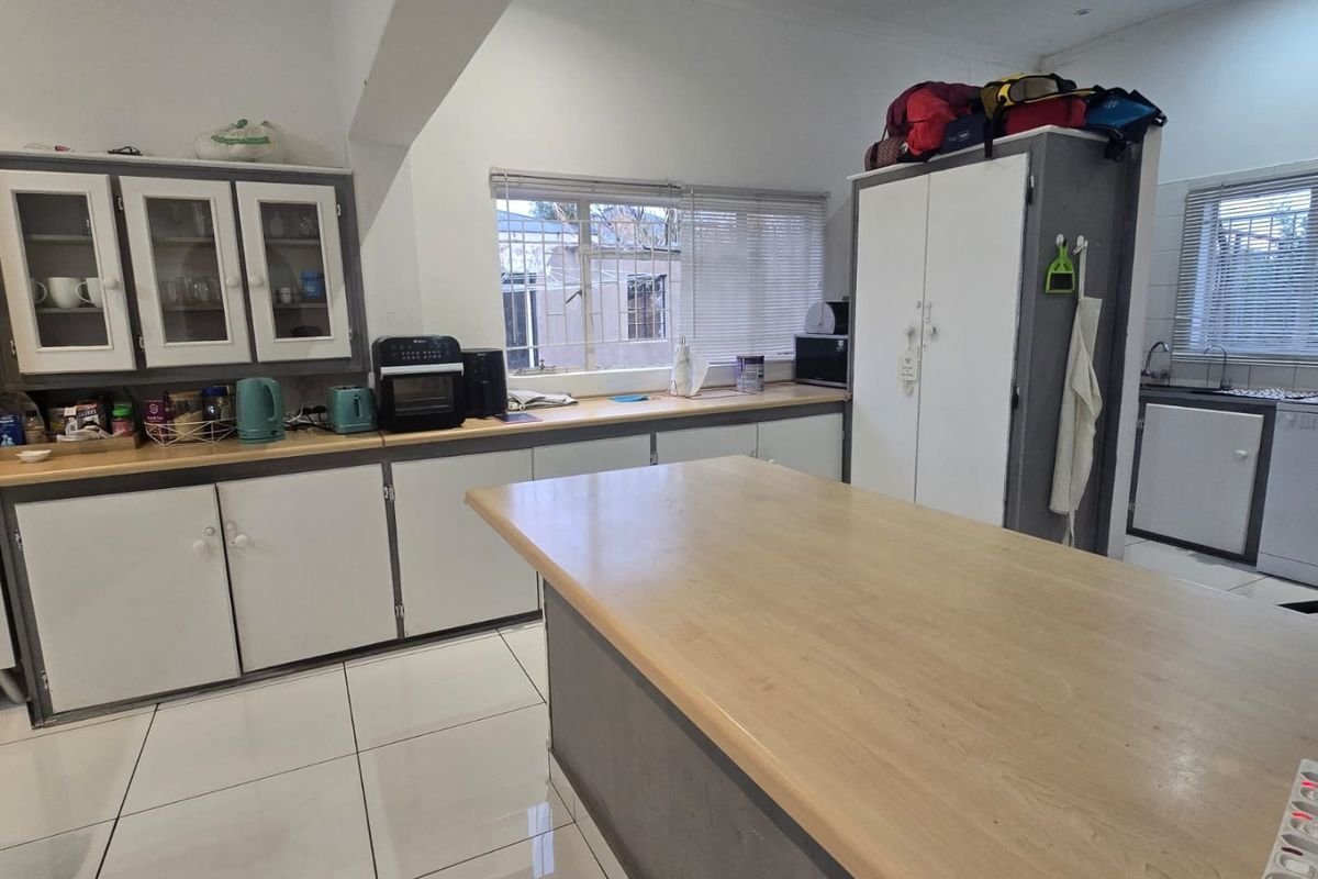 A functional kitchen featuring ample cabinetry, a central island with laminate countertops, and tiled flooring, offering a practical layout for daily meal preparation.