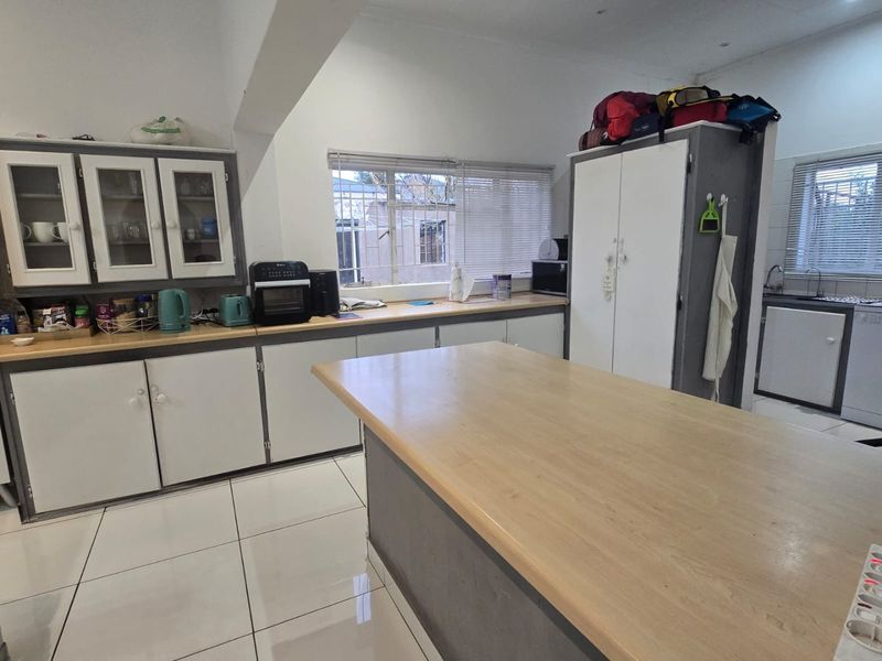 A functional kitchen featuring ample cabinetry, a central island with laminate countertops, and tiled flooring, offering a practical layout for daily meal preparation.