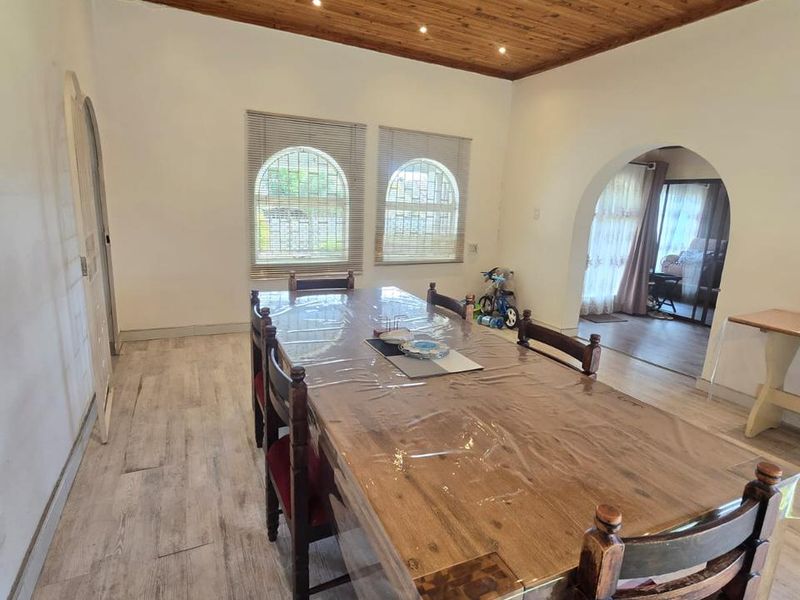Spacious dining room featuring a warm timber tongue and groove ceiling, recessed lighting, arched architectural details, and modern laminate flooring.