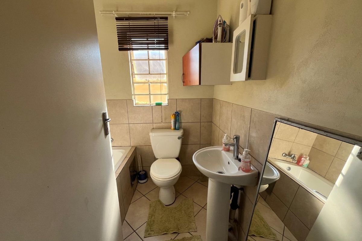 A functional bathroom featuring a pedestal basin, toilet, and built-in bathtub with tiled walls and flooring.