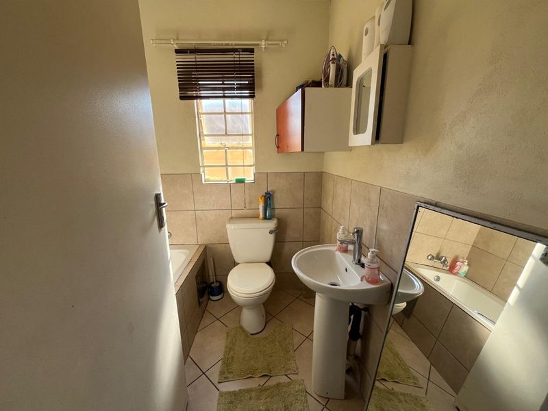 A functional bathroom featuring a pedestal basin, toilet, and built-in bathtub with tiled walls and flooring.