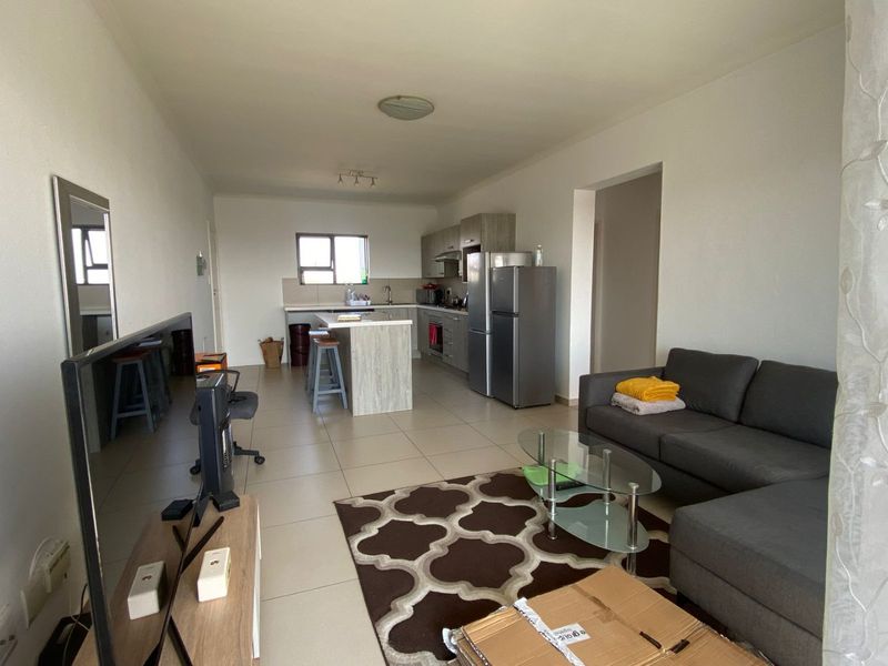 Open-plan living and kitchen area featuring tiled floors, a central kitchen island, and built-in cabinetry with integrated appliances.