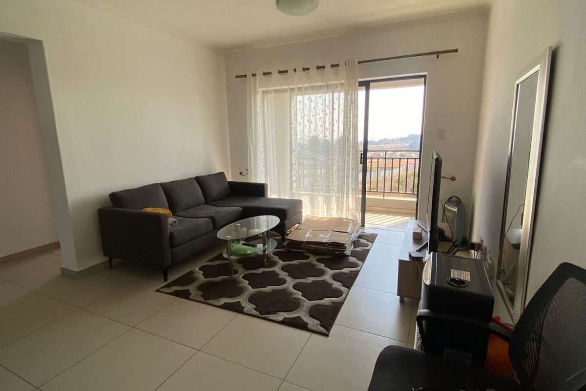 A living room featuring tiled flooring and a sliding glass door providing access to a balcony, offering natural light and outdoor connectivity.