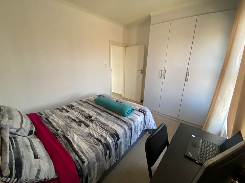 A functional bedroom featuring built-in cupboards and neutral carpeting, providing a clean and practical living space.