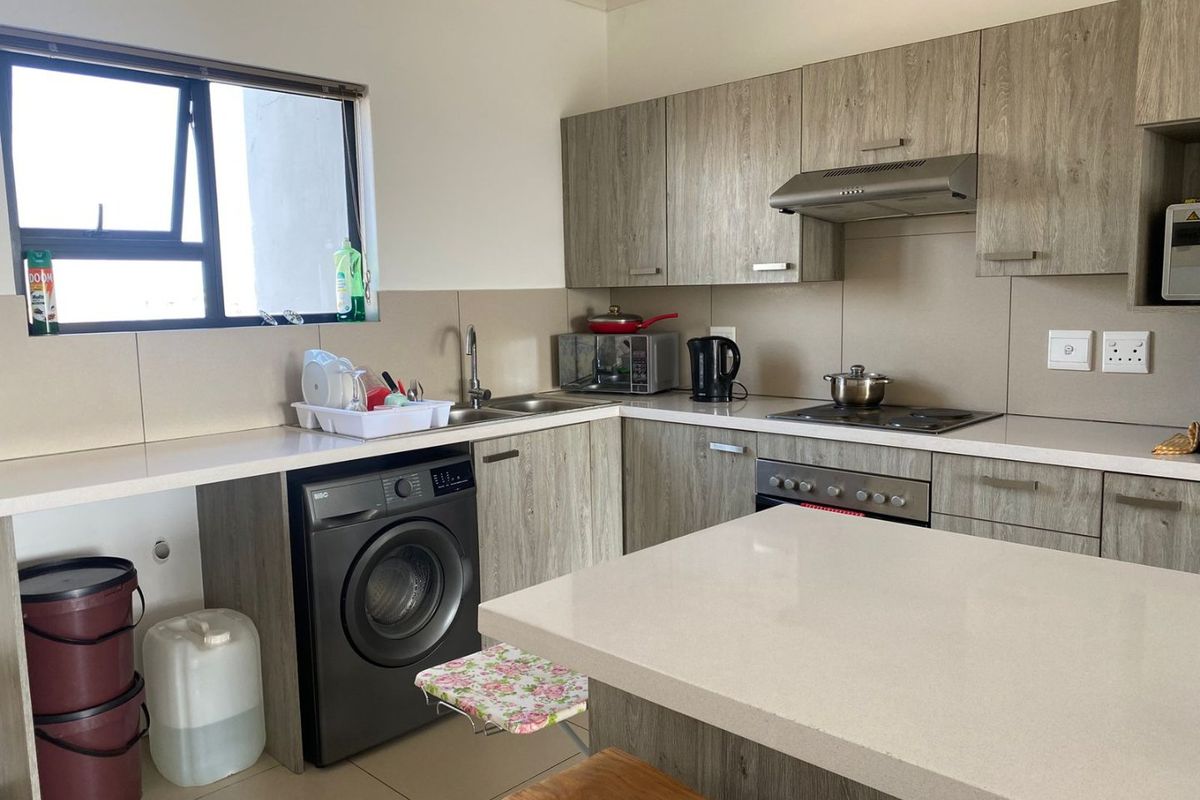 Modern kitchen featuring wood-grain cabinetry, stone countertops, integrated appliances, and a functional kitchen island with breakfast bar seating.