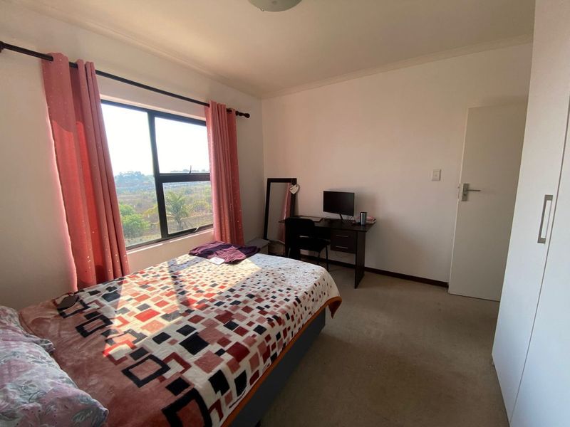 A bedroom featuring carpeted flooring, a built-in wardrobe, and a large window providing natural light and scenic views.