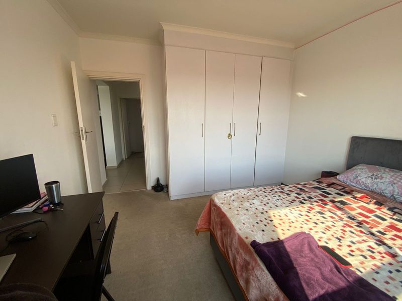 A bedroom featuring built-in cupboards, carpeted flooring, and coving, providing a functional living space with direct access to the hallway.
