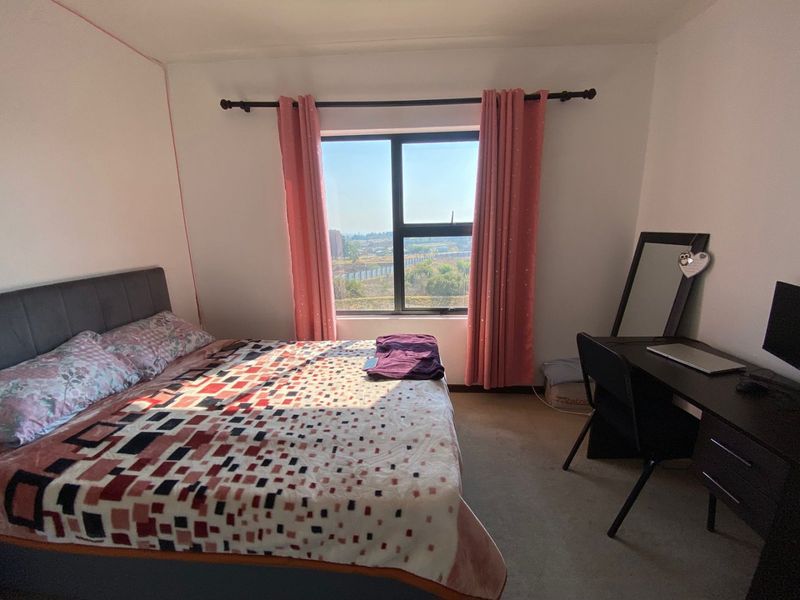 A bedroom featuring carpeted flooring and an aluminium-framed window with views, providing a functional living space.