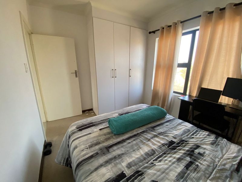 A functional bedroom featuring a built-in wardrobe, neutral wall finishes, and natural light through the window.