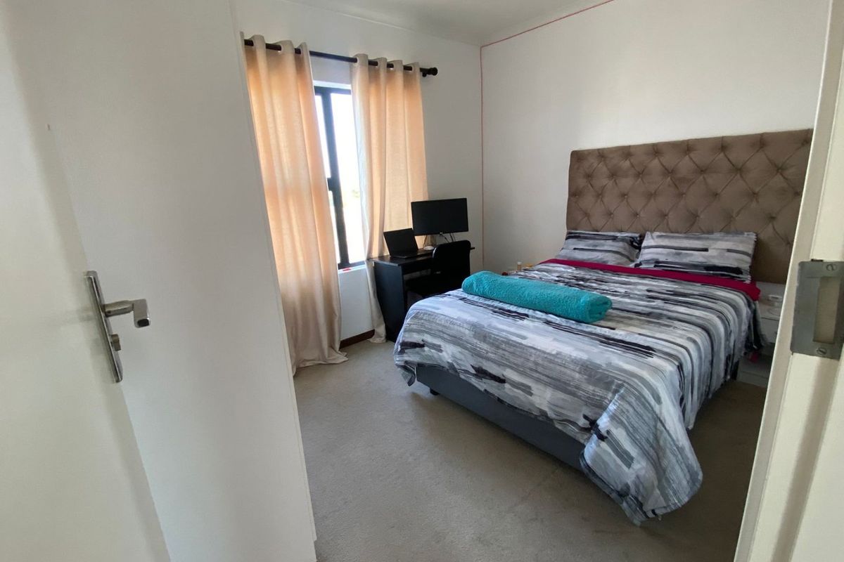 A functional bedroom featuring carpeted flooring and a window, providing a comfortable space for rest.