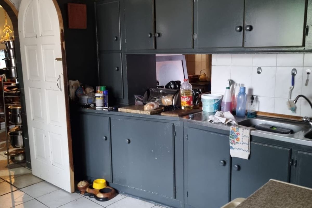 A functional kitchen featuring dark painted cabinetry, tiled backsplash, and a timber ceiling, offering potential for a modern cosmetic update.
