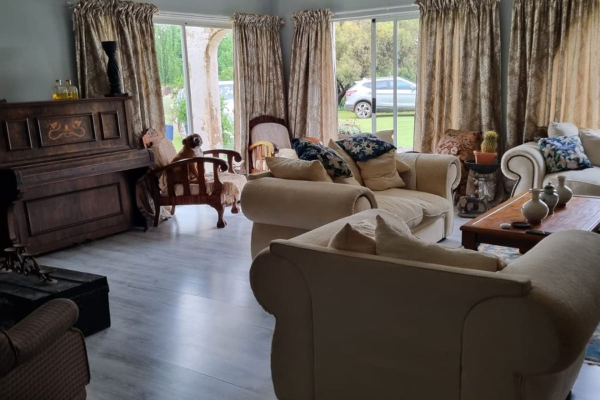 Spacious living room featuring laminate flooring, a beadboard ceiling, wrought iron chandelier, and large sliding glass doors providing access to the garden.