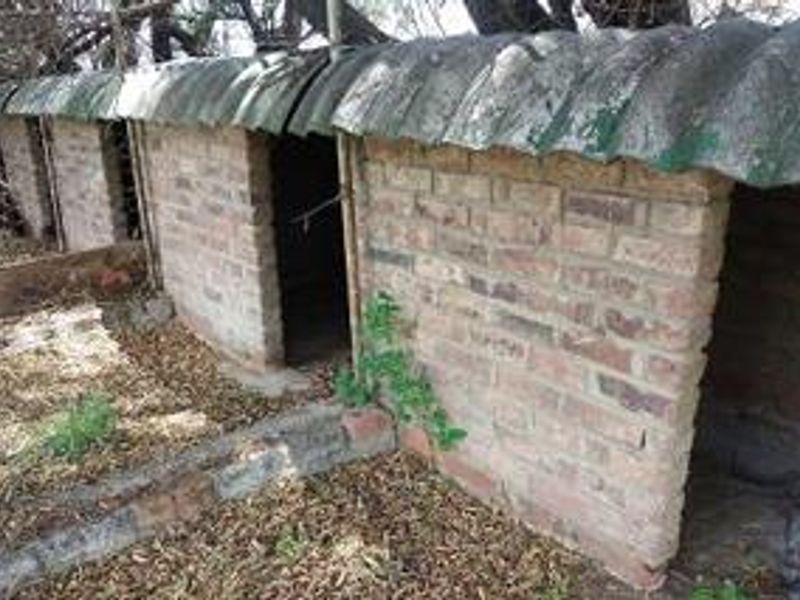 A row of basic brick utility structures with corrugated roofing, suitable for farm storage or animal housing.
