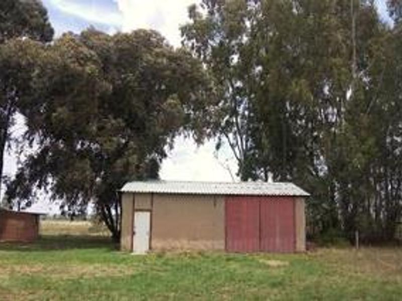 A detached utility shed or storage building on the farm property, featuring a corrugated metal roof and large sliding barn-style doors.