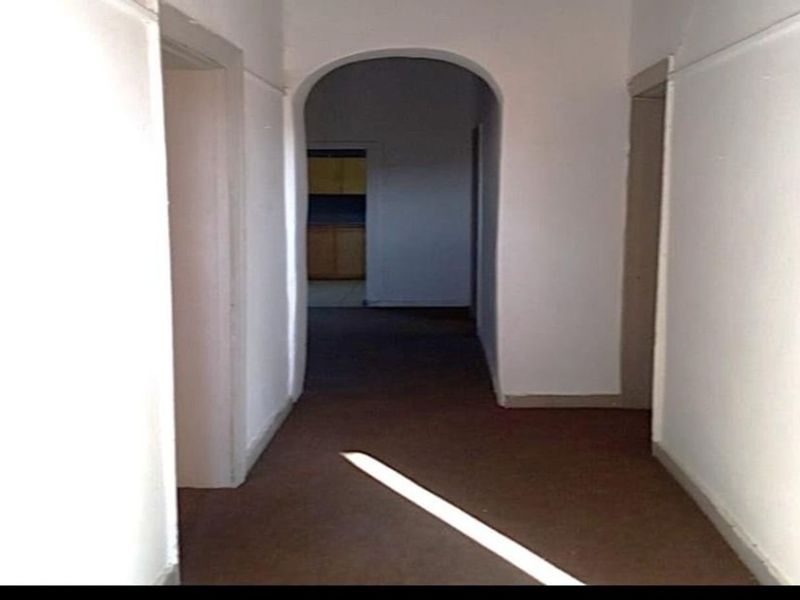 A vacant interior hallway featuring an arched transition and multiple doorways leading to adjacent rooms.