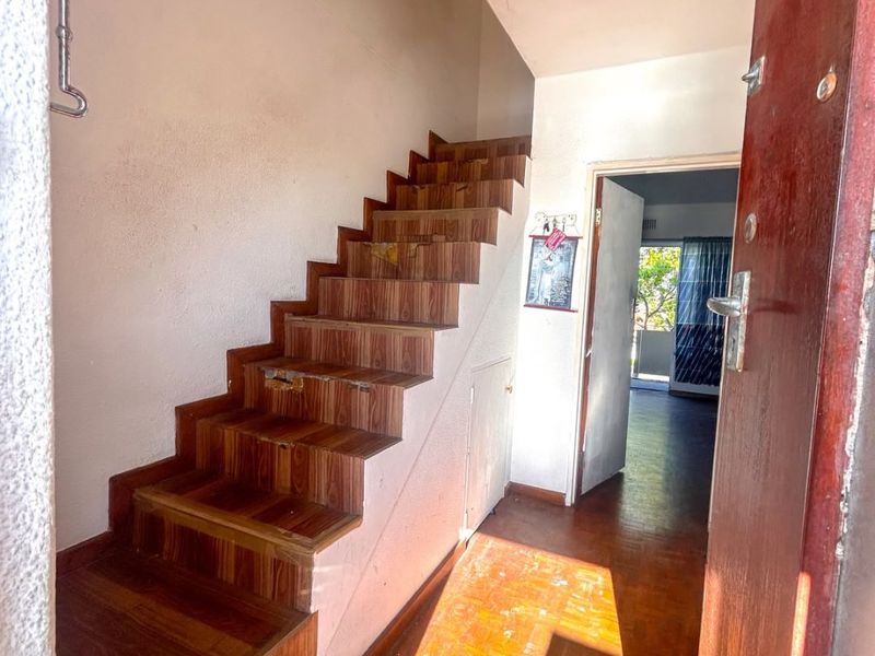 Entrance foyer featuring a wooden staircase with under-stair storage and parquet flooring, leading through to the main living area.