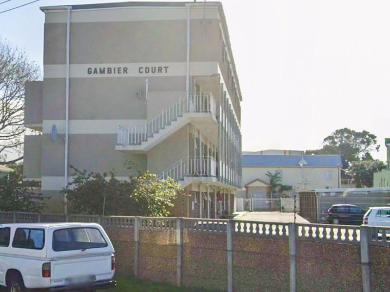 Exterior view of Gambier Court apartment building featuring an external staircase and a secure precast concrete boundary wall.