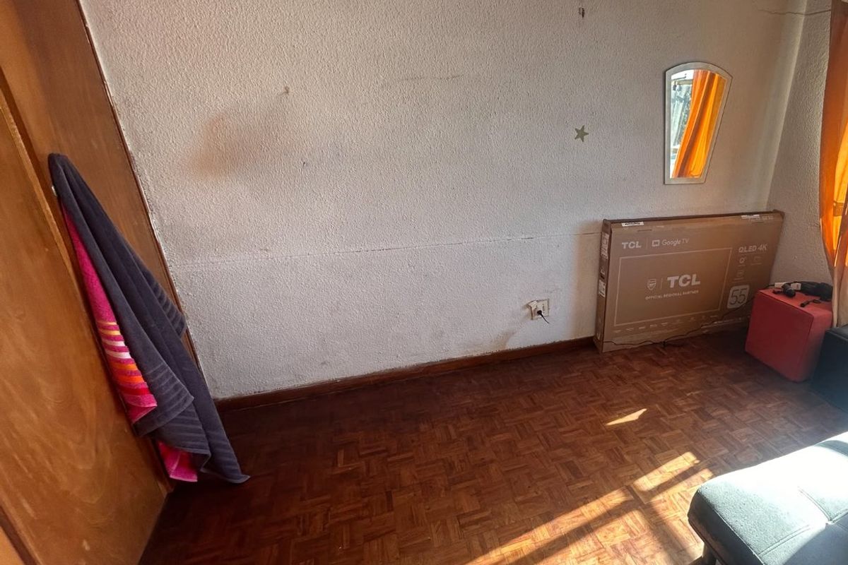 A bedroom featuring original parquet flooring and a built-in wardrobe, requiring cosmetic updates to the wall finishes and general maintenance.