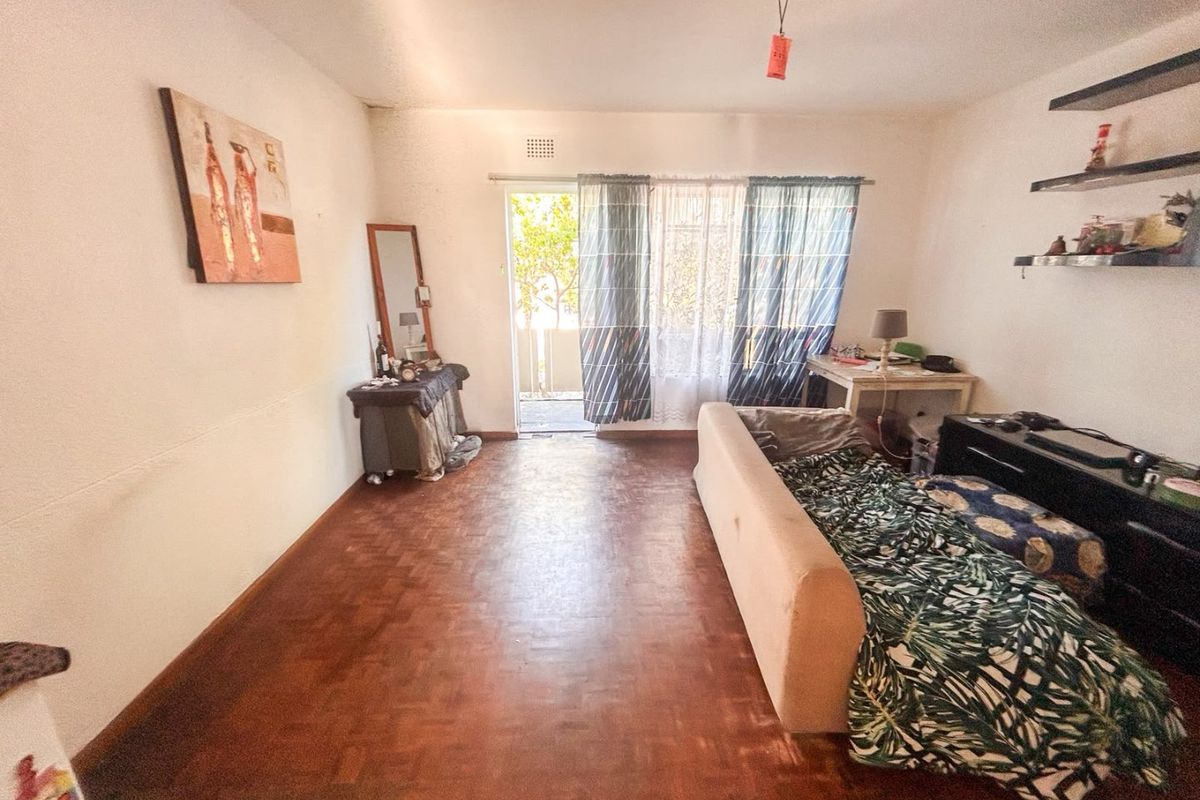 A living room featuring traditional parquet flooring and a sliding glass door leading to an outdoor area, offering a blank canvas for renovation.