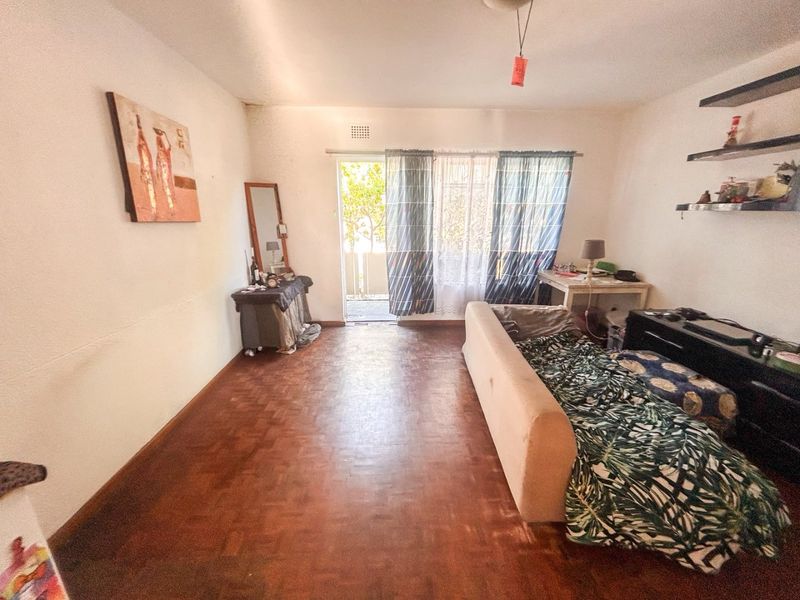 A living room featuring traditional parquet flooring and a sliding glass door leading to an outdoor area, offering a blank canvas for renovation.