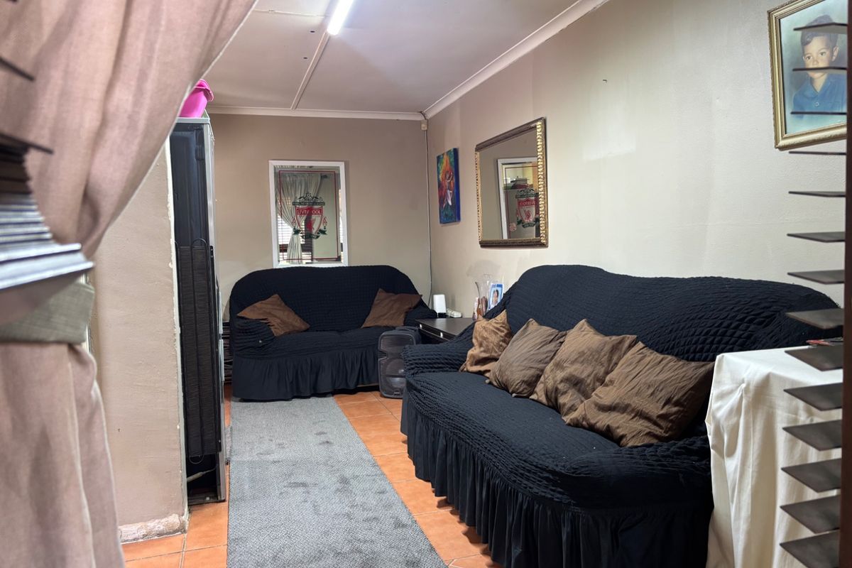 A living room area featuring tiled flooring and coved ceilings, currently furnished with seating.