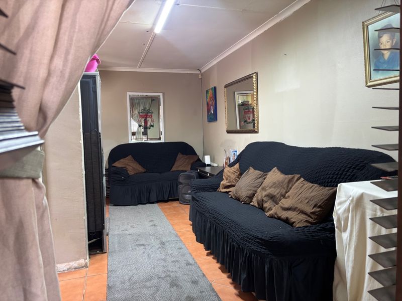 A living room area featuring tiled flooring and coved ceilings, currently furnished with seating.