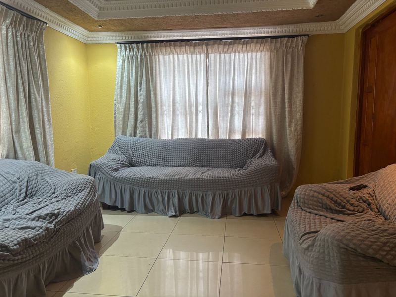A living room featuring tiled flooring and decorative ceiling cornicing with recessed detailing.