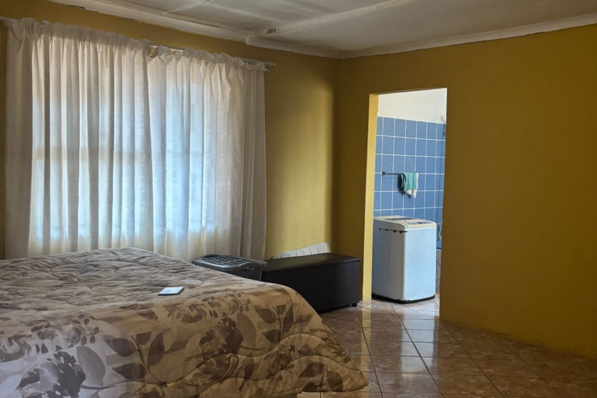 A bedroom featuring tiled flooring and direct access to an adjacent utility area, requiring cosmetic updates to the ceiling and wall finishes.