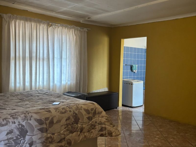 A bedroom featuring tiled flooring and direct access to an adjacent utility area, requiring cosmetic updates to the ceiling and wall finishes.