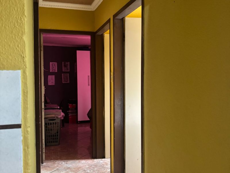 A functional hallway featuring tiled flooring and ceiling cornice, providing access to adjacent rooms within the home.