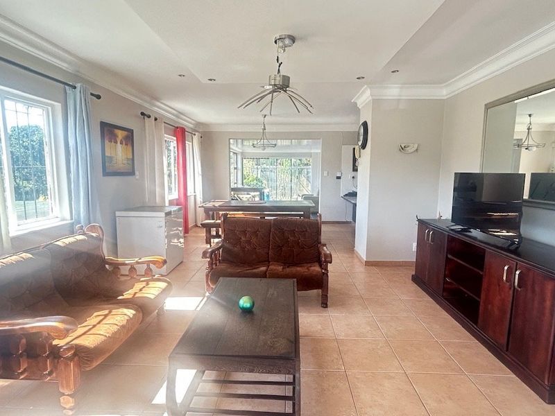 Spacious open-plan living area featuring tiled flooring, recessed ceiling lighting, and decorative cornicing, providing a versatile layout for dining and relaxation.