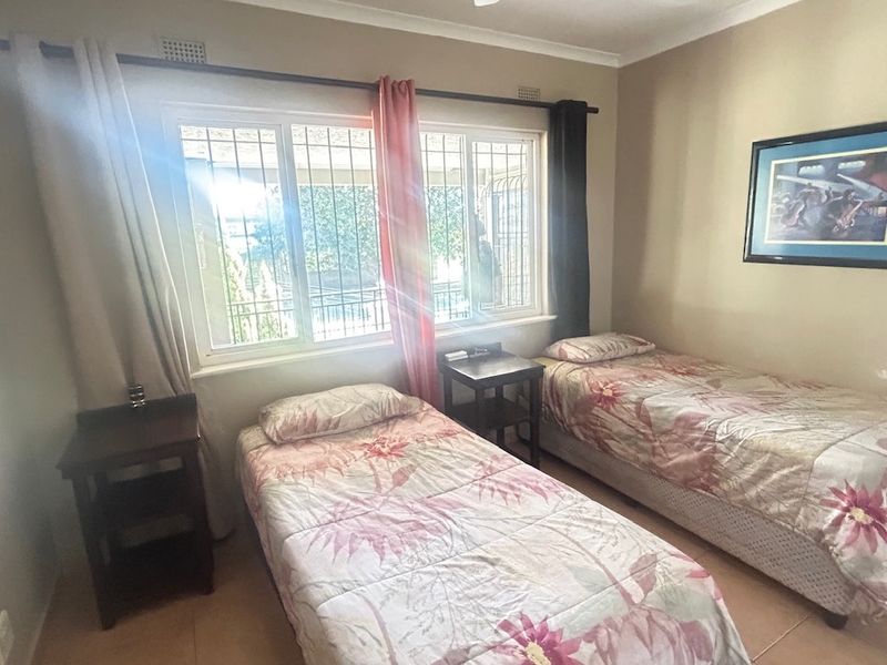 A bedroom featuring tiled flooring, a ceiling fan, and windows fitted with security bars.