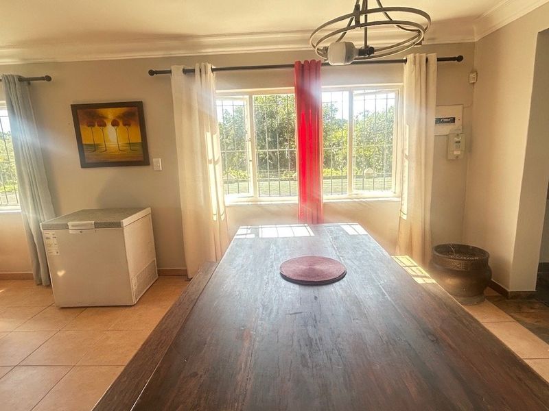 A dining area featuring tiled flooring, security bars on windows, and recessed lighting, providing a functional space for family meals.