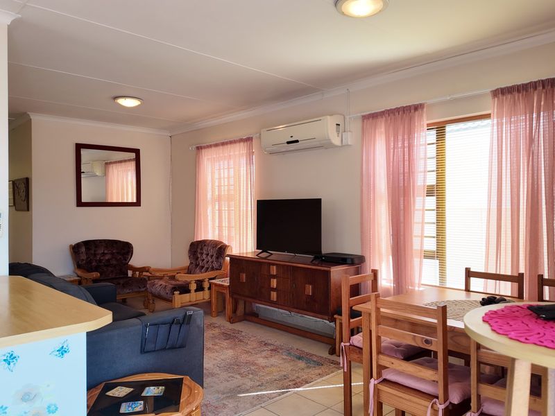Open-plan living and dining area featuring tiled flooring, split-system air conditioning, and natural light through large windows.
